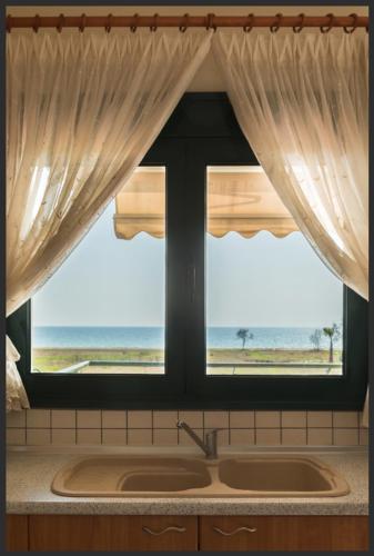 a kitchen window with a view of the beach at Oxana house in Nea Moudania