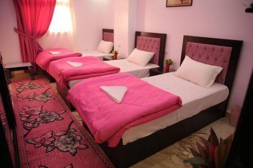 três camas num quarto com lençóis cor-de-rosa em Queen Pyramids View Inn no Cairo