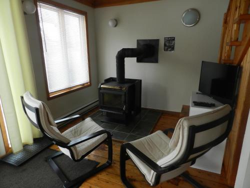 a living room with two chairs and a wood stove at Maison Chez Laurent in Baie-Saint-Paul