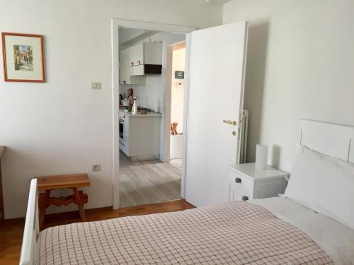 カルドナッツォにあるAppartamento Balùの白いベッドルーム(ベッド1台付)、キッチンが備わります。