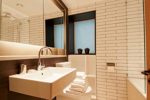ein weißes Badezimmer mit einem Waschbecken und einem Spiegel in der Unterkunft Wigmore Suites Serviced Apartments by Globe Apartments in London