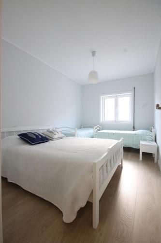 a white bedroom with a large white bed and a window at Salinas Beach House - T3 Apartment - Costa Nova in Costa Nova