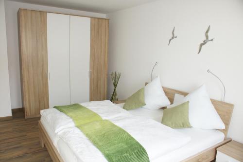 Schlafzimmer mit einem Bett mit grünen und weißen Kissen in der Unterkunft Ferienwohnung Störtebekersuite in Glowe