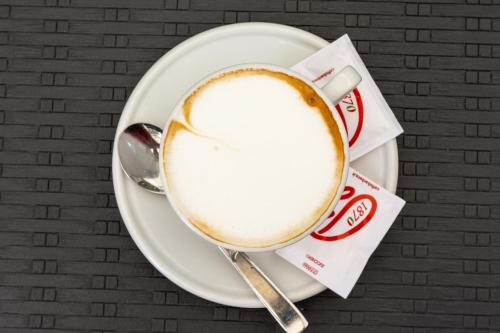 a cup of coffee on a plate with a spoon at B&B Cairoli in Messina