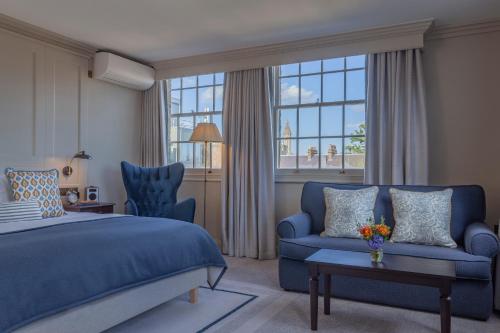 1 dormitorio con 1 cama azul y 1 sofá en Richmond Hill Hotel, en Richmond upon Thames