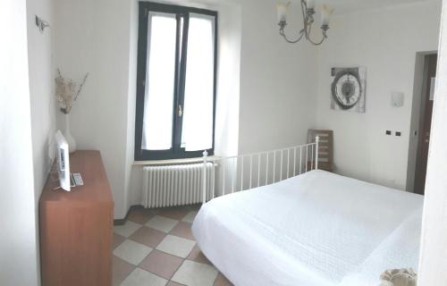 a white bedroom with a bed and a window at Hotel Villa San Fedele in San Fedele Intelvi