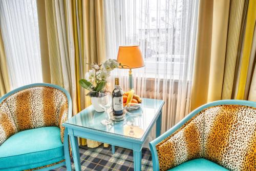a table with a vase of flowers on it next to two chairs at Chateau Fontenay in Bad Wörishofen