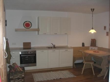 a kitchen with white cabinets and a table and a sink at Haus Milli in San Candido