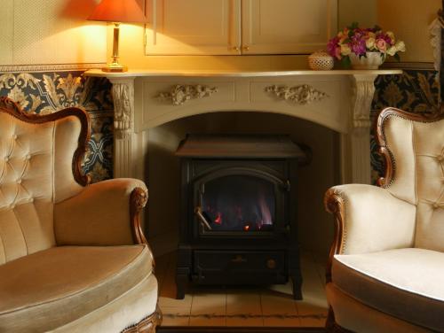 a living room with a fireplace and two chairs at Hotel Pegasus in Apeldoorn