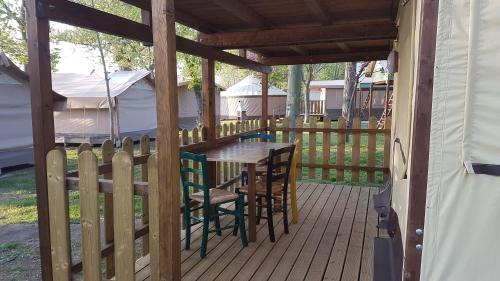 een houten terras met een tafel en stoelen aan een hek bij Parco Del Lago Glamping And Lodges in Anguillara Sabazia