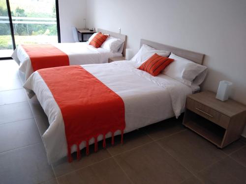 two beds with red and white sheets in a room at Hotel Boutique La Ceiba in Quimbaya