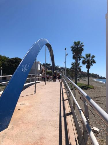 a metal bridge over a beach with palm trees at Apartamentos casa Tia Antonia in Málaga