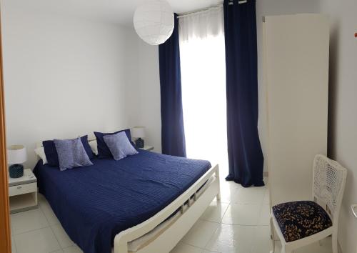 a bedroom with a bed with blue sheets and a window at Apulia Beach in Leporano