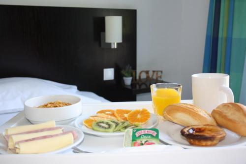 a tray of breakfast foods and orange juice on a bed at Flag Hotel Santarém in Pernes