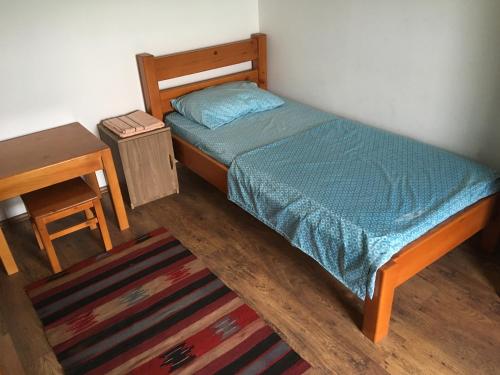 Cama pequeña en habitación con mesa y alfombra en Twins V.V.T Hostel, en Orešani