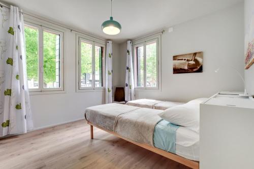 a white bedroom with two beds and windows at Lido's Garden Apartment in Venice-Lido