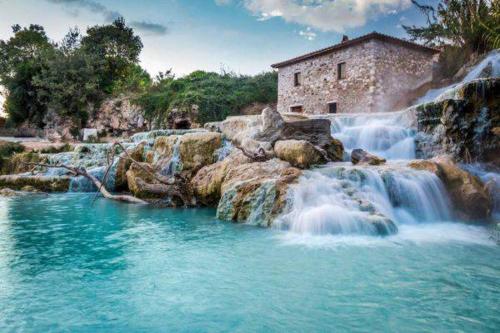 a waterfall with a building in the middle of it at Il Nido del Falco nelle Antiche Mura in Saturnia