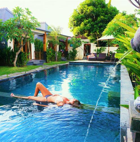 a woman in a bikini laying in a swimming pool at Singabu Bungalows in Nusa Penida