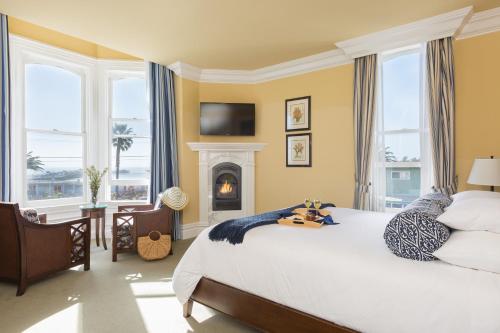 a bedroom with a large bed and a fireplace at West Cliff Inn, A Four Sisters Inn in Santa Cruz