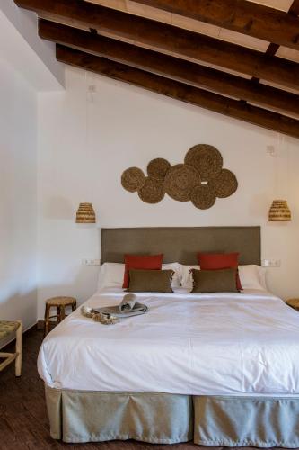a bedroom with a large bed with white sheets at Curolla Petit Hotel in Maria de la Salut