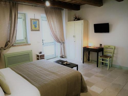 a bedroom with a bed and a desk and a television at Le Maraclà Country House in Iesi