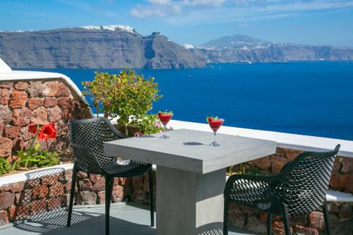 een tafel en stoelen met uitzicht op de oceaan bij White Pearl Villas in Oia