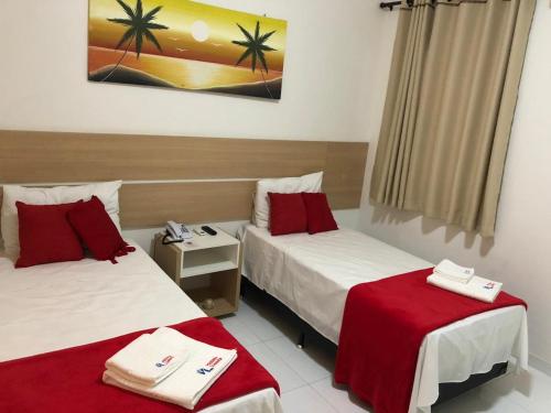 a hotel room with two beds with red sheets at POUSADA LUNARA in Jequié