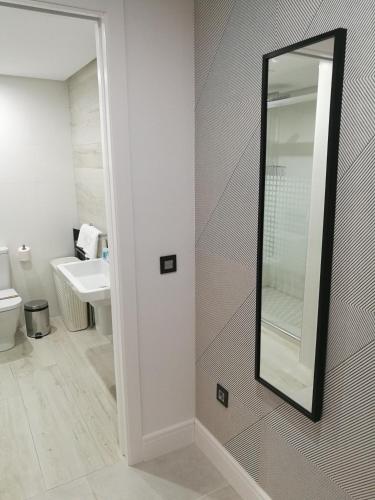 a bathroom with a mirror and a sink at Apartamentos Las Palmeras in Palma del Río