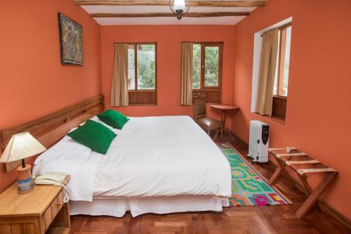 a bedroom with a large bed with orange walls at SAUCE Hotel Boutique in Ollantaytambo