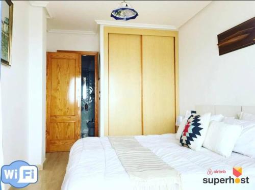 a bedroom with a white bed and a wooden door at Mar Menor, La Manga Strip/Best view + Pool in San Blas