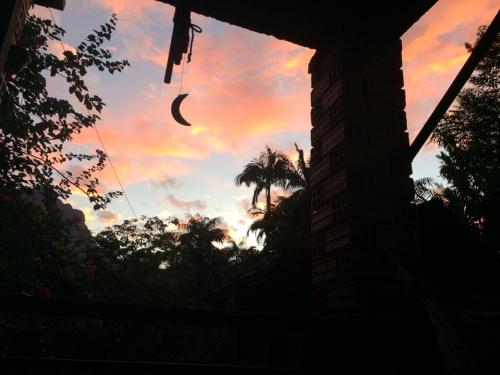 a sunset with a palm tree in the sky at Pousada do Oasis in Morretes