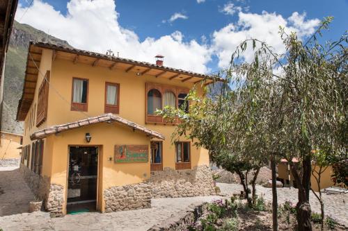 een geel huis met een deur ervoor bij SAUCE Hotel Boutique in Ollantaytambo