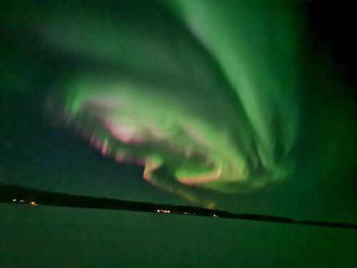 an airplane is flying in the sky with green lights at Ollilan Lomamajat in Kuusamo