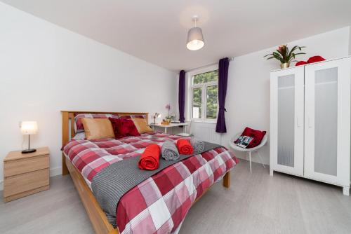 ein Schlafzimmer mit einem großen Bett mit roten Kissen in der Unterkunft Childs Hill Vacation Home in London