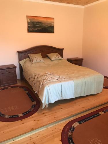 a bed in a bedroom with two rugs on the floor at Садиба у Вишкові in Vyshkiv