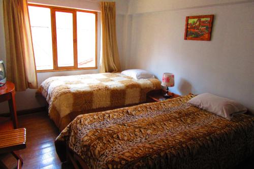 a hotel room with two beds and a window at Hospedaje Kamila in Cusco