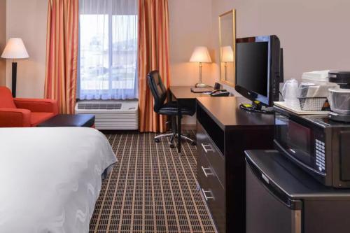 a hotel room with a bed, desk and television at Hotel Nova SFO By FairBridge in South San Francisco