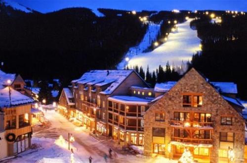 a large building with a snow covered mountain in the background at River Run Village in Keystone