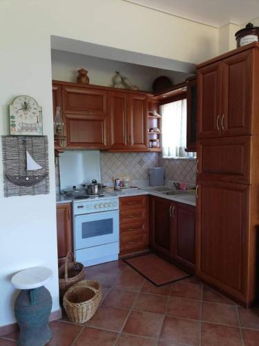 a kitchen with wooden cabinets and a white stove at Kalivakia View in Tsoukaladhes