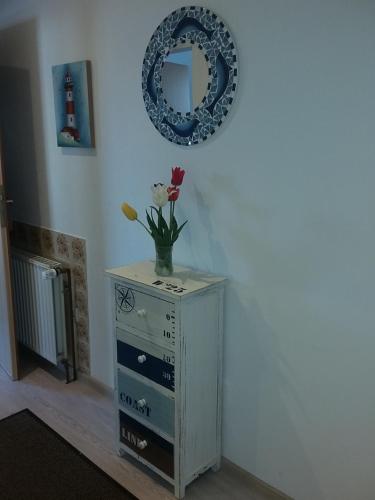 a vase of flowers on a dresser with a mirror at Pension Haus Erika in Cuxhaven