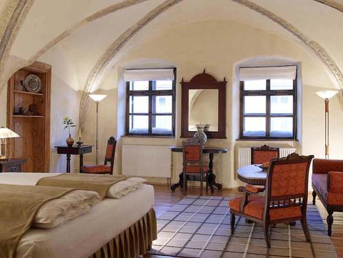 Un dormitorio con una cama y una mesa y sillas. en Fronius Boutique Residence, en Sighişoara