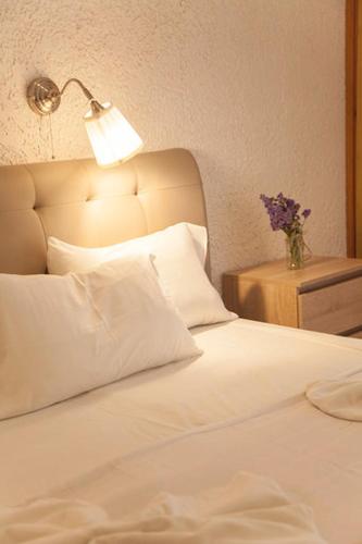 a white bed with a lamp and a vase of flowers at Gioma Hotel in Agia Galini