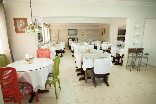 uma sala de jantar com mesas e cadeiras brancas em Royal Plaza Hotel em Apucarana