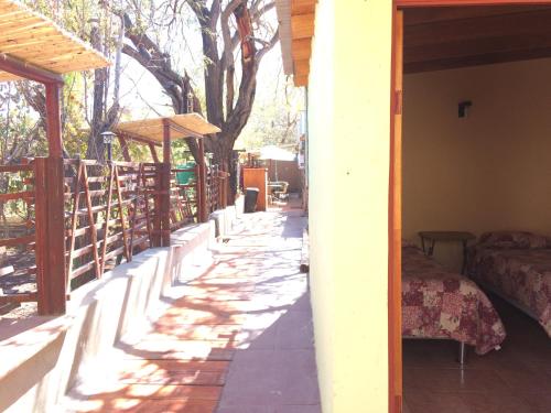 a porch of a house with a bed and trees at Refugio Don Natu in San Pedro de Atacama