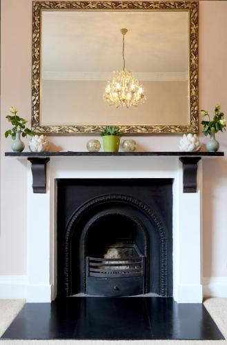 a fireplace with a mirror and a chandelier at Southcot Place, Apartment With Garden in Bath