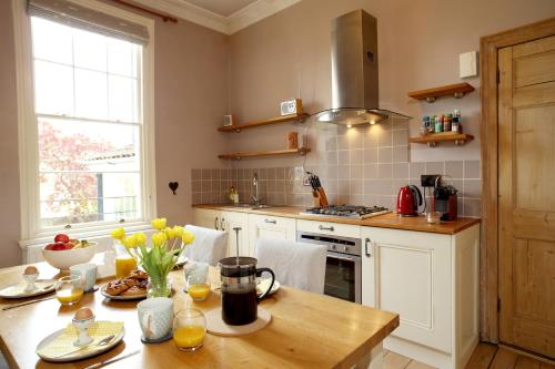 a kitchen with a wooden table with yellow flowers on it at Southcot Place in Bath