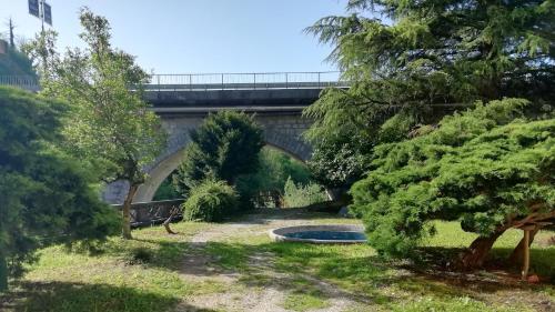 a bridge over a park with a pond and trees at Apartma Humar in Tolmin