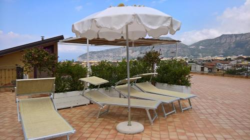 un grupo de sillas y una sombrilla en un patio en Villa Flavia en Sant'Agnello