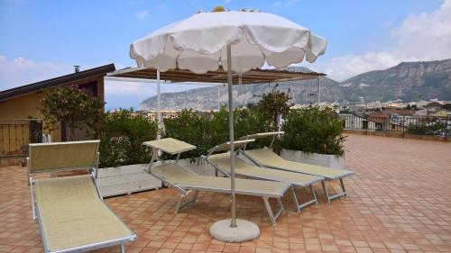 een groep stoelen en een parasol op een patio bij Villa Flavia in Sant'Agnello