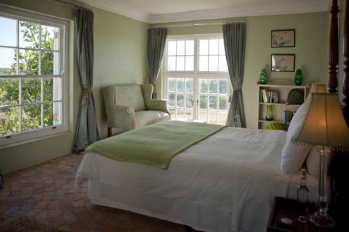 a bedroom with a bed and a chair and windows at Hawksmoor House in Stellenbosch